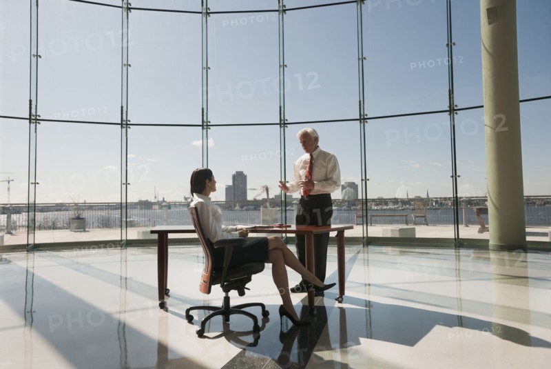 Business people working in large office with glass wall