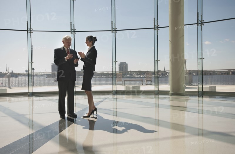 Business people talking in office lobby with glass wall