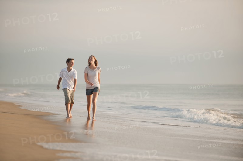Caucasian brother and sister walking on beach