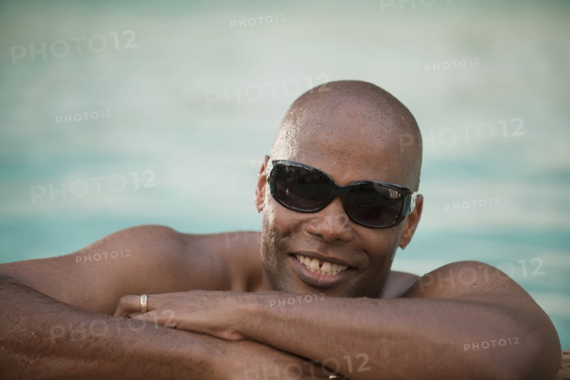 Smiling African American man leaning on edge of swimming pool
