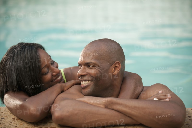 African American couple leaning on edge of swimming pool