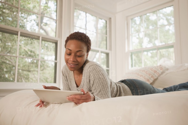 African American woman using digital tablet in bed