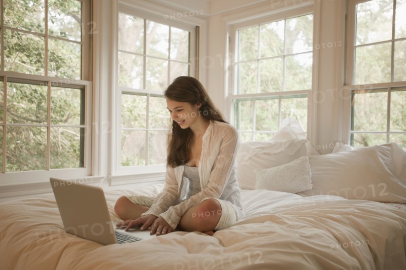 Mixed race girl using laptop in bed