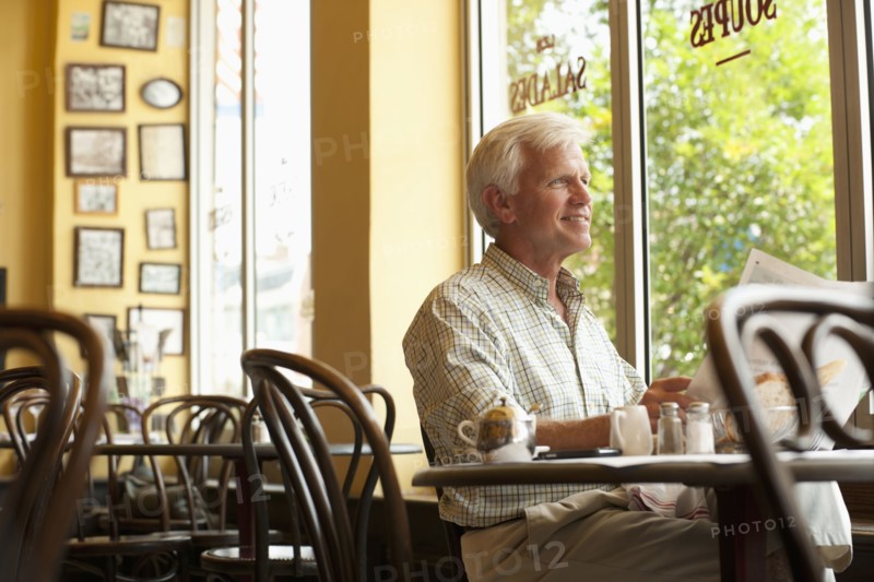 Caucasian man reading newspaper in restaurant