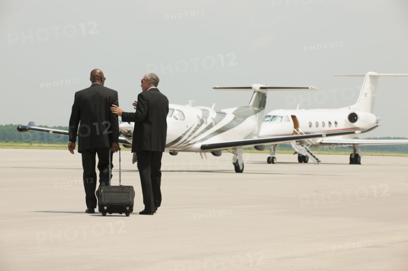 Businessmen walking on airport tarmac