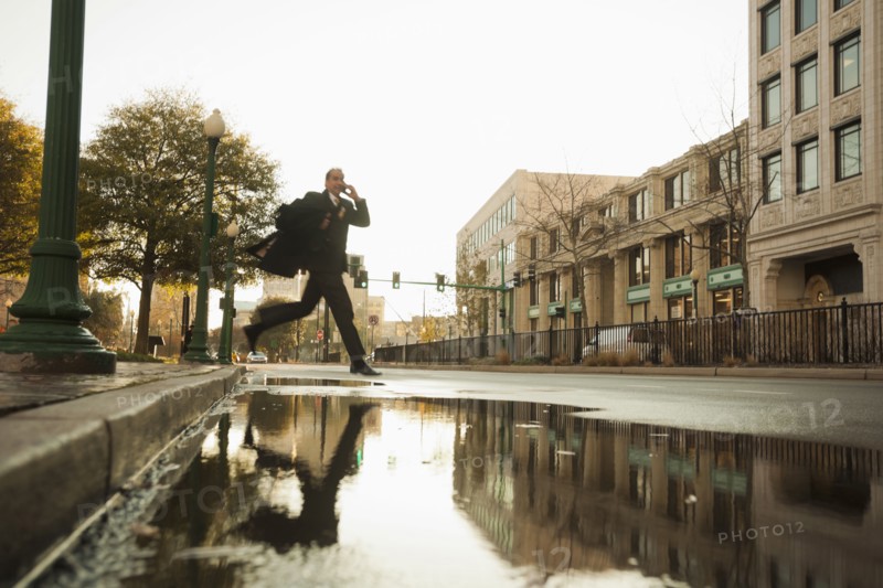 Caucasian businessman jumping over urban puddle
