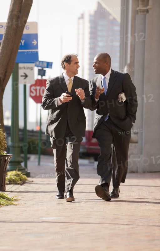 Businessmen walking together on city sidewalk