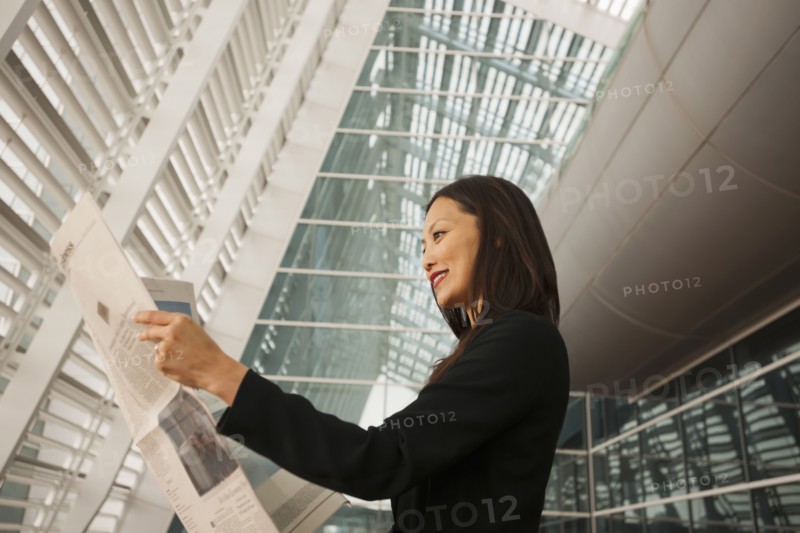 Asian businesswoman reading newspaper
