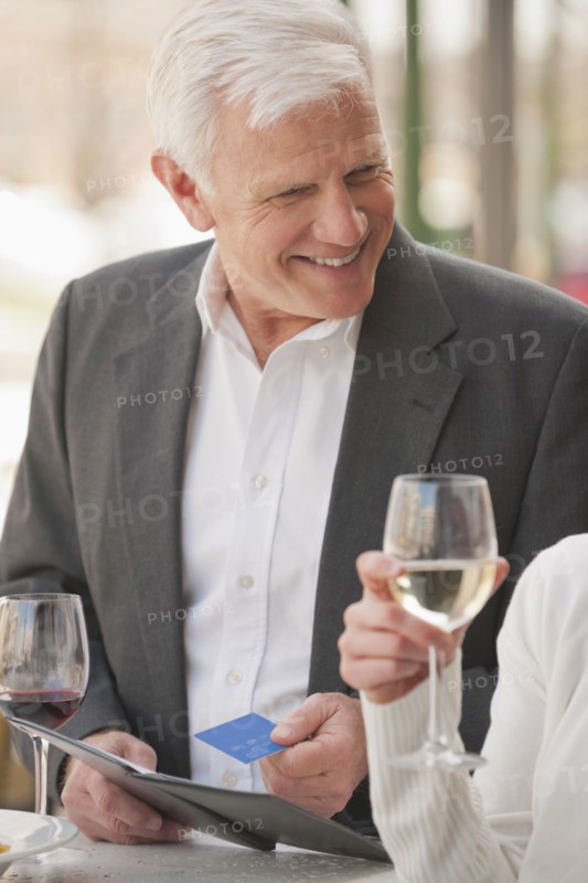 Caucasian couple drinking wine and paying bill