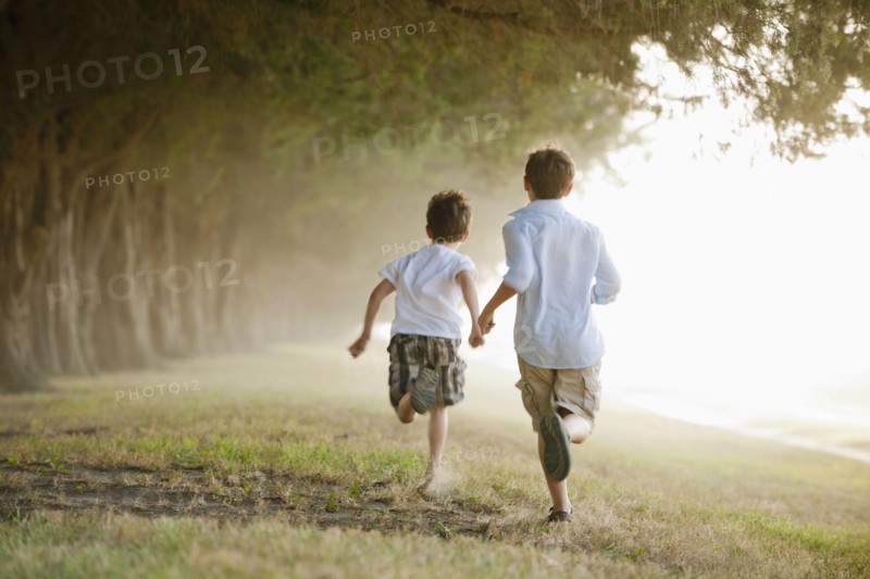Caucasian boys running in orchard