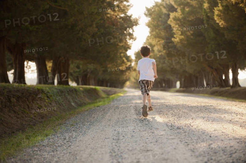 Caucasian boy running on dirt road