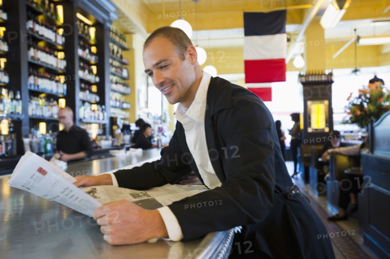 Caucasian man reading newspaper in cafe