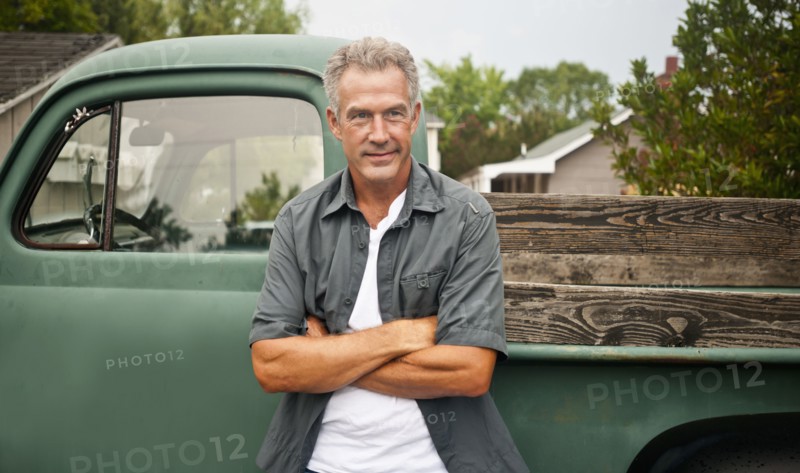 Caucasian farmer leaning against truck outdoors