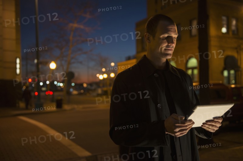 Caucasian man using tablet computer on city street