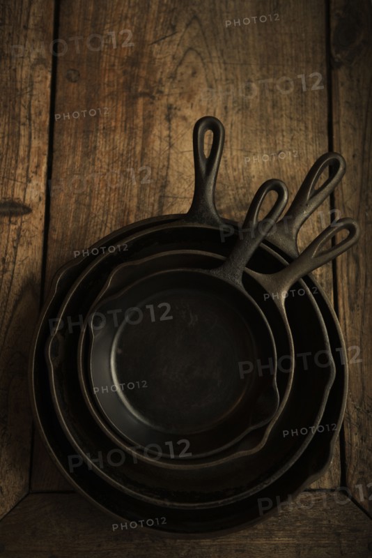 Empty cast iron pans on wooden board