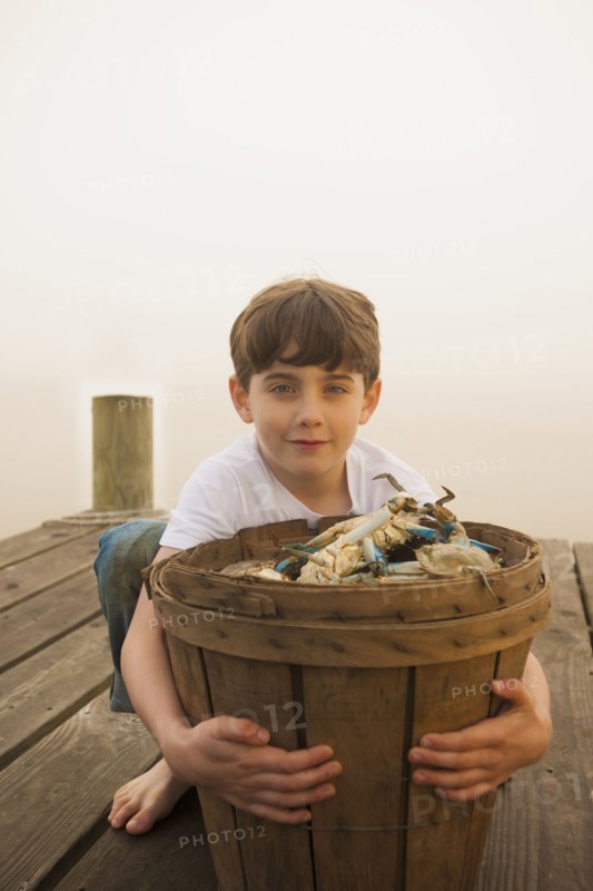 Caucasian boy holding basket of crabs