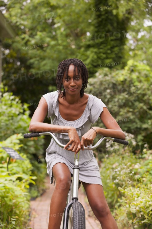 African American woman sitting on bicycle in backyard