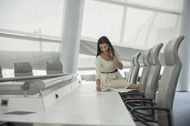 Mixed race businesswoman on cell phone in conference room
