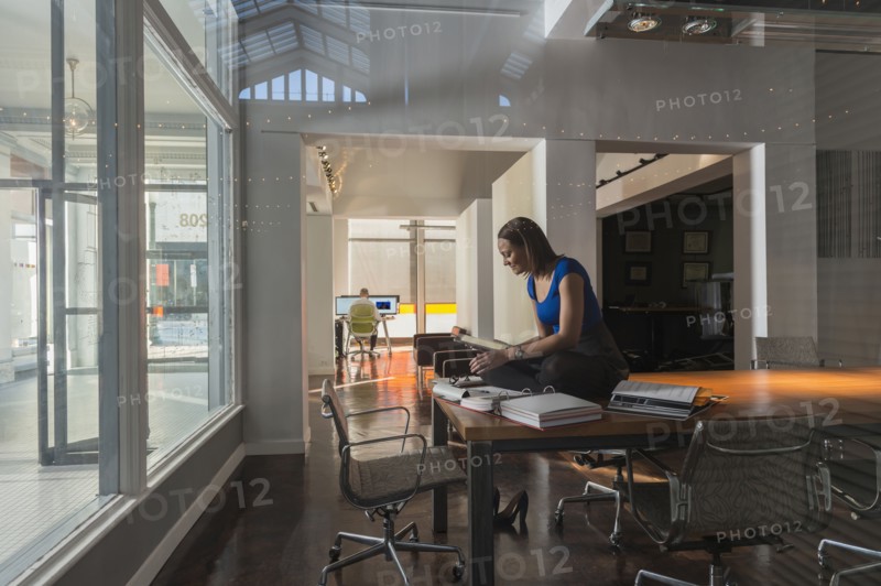 Mixed race businesswoman sitting on conference table