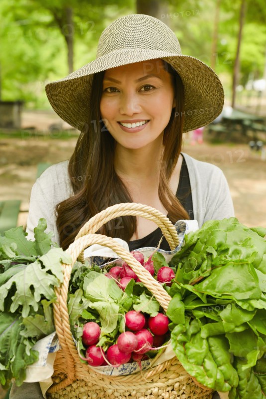 Asian woman carrying basket of produce