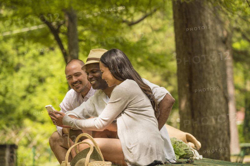 Friends using cell phone on picnic table