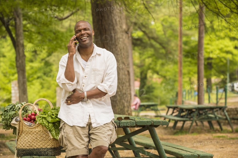 African American man talking on cell phone on picnic table