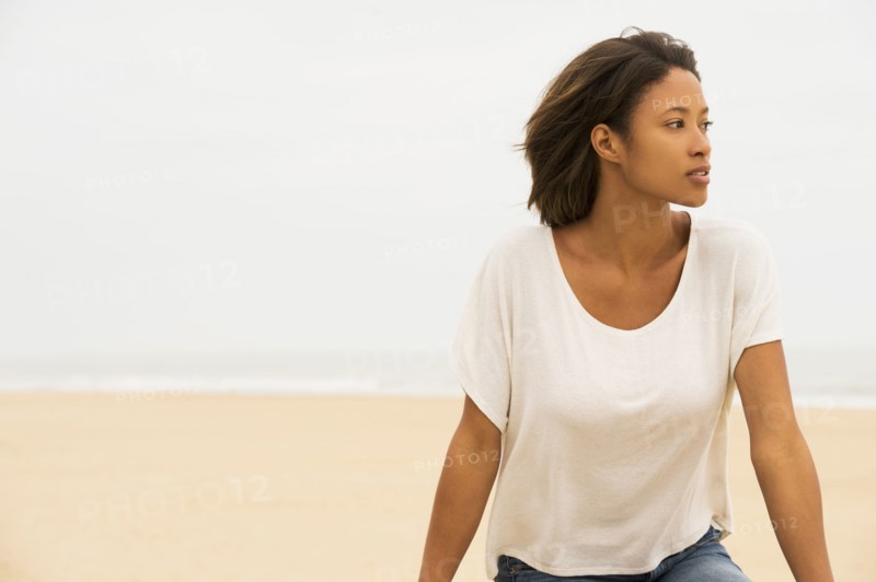 Pensive African American woman sitting at beach