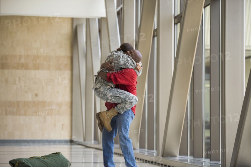 African American soldier hugging husband in airport