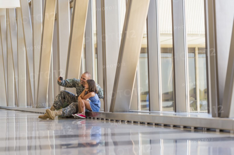 Returning soldier taking selfie with daughter in airport