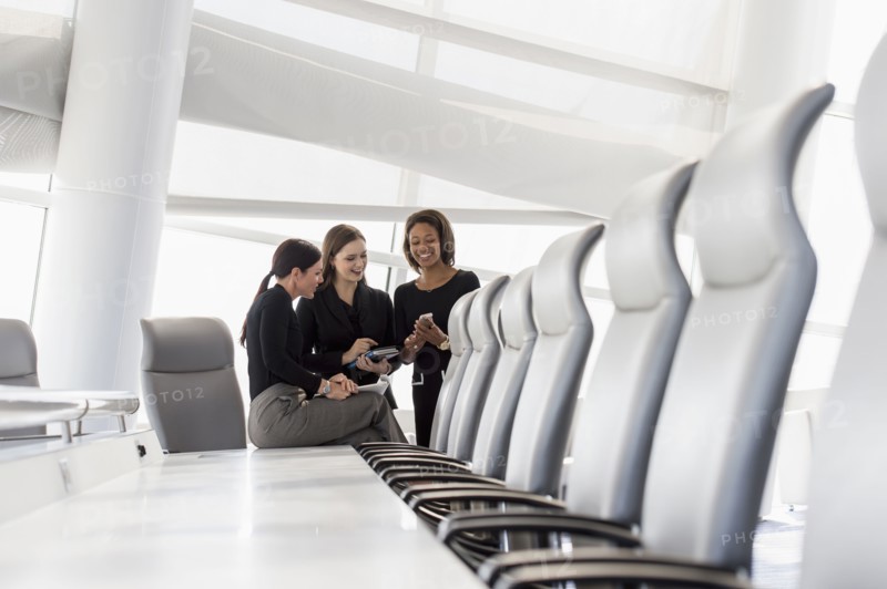 Businesswomen using cell phone in conference room