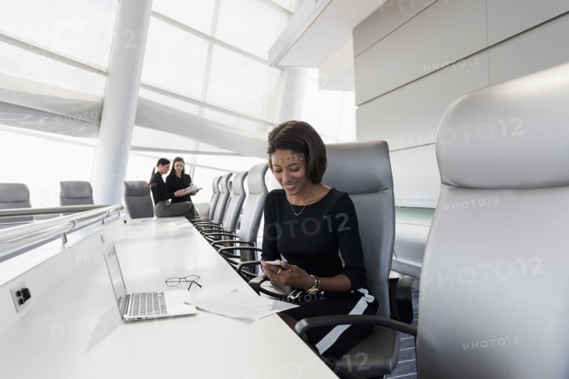 Businesswoman using cell phone in conference room
