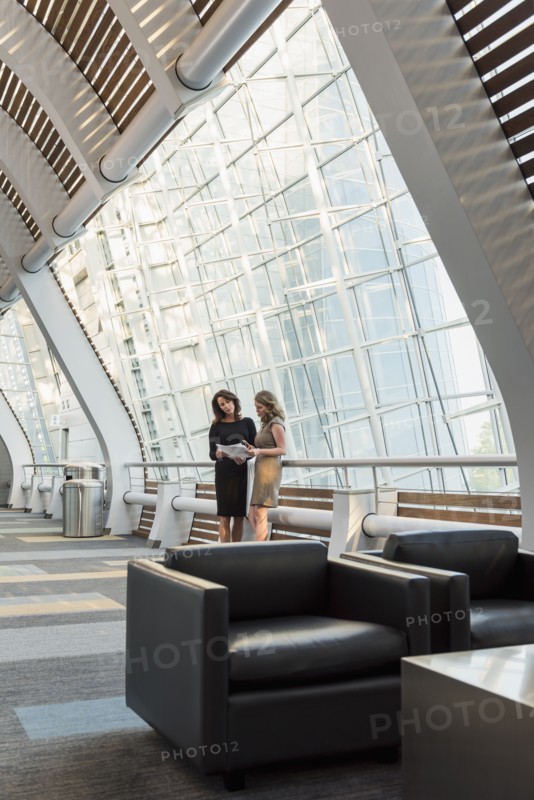 Caucasian businesswomen holding paperwork and talking