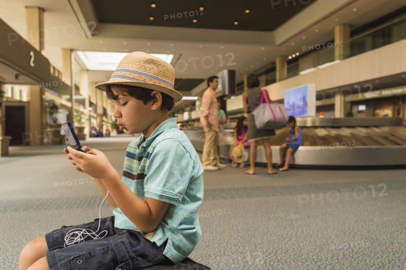 Boy playing on cell phone in airport