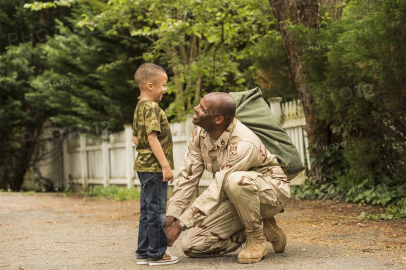 African American soldier tying shoelace for son