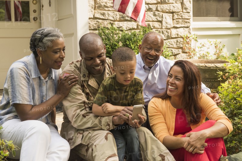 Soldier and multi-generation family looking down at cell phone