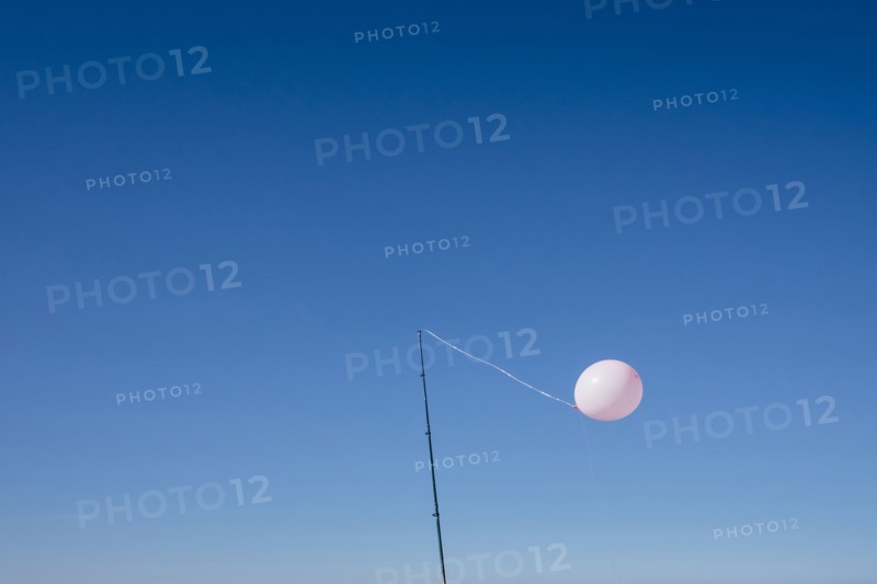 Balloon tied to pole in blue sky