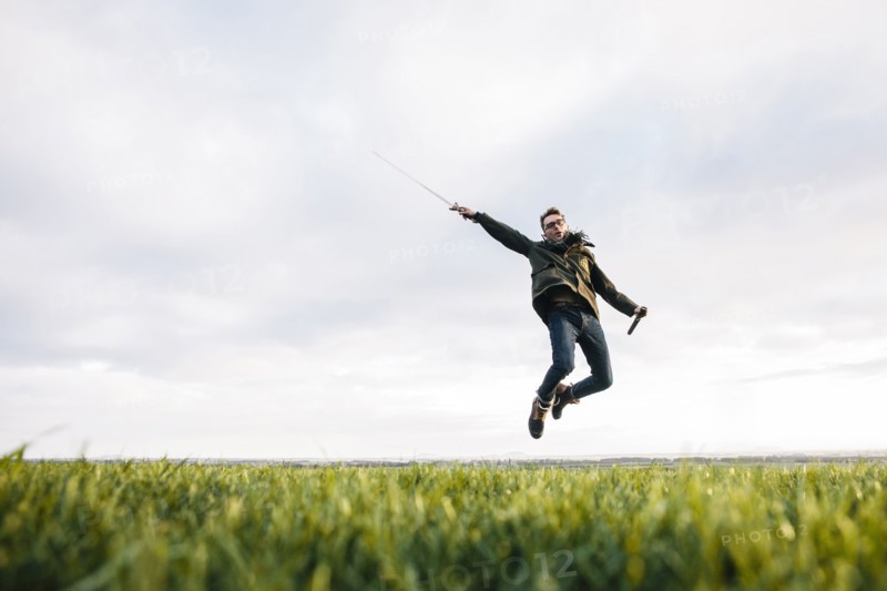 Caucasian man unsheathing sword in field