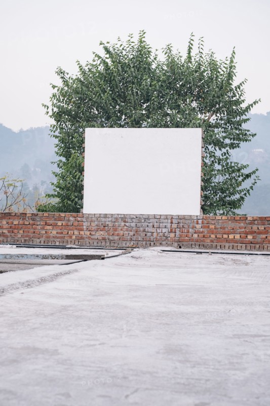 Blank board on brick wall near tree