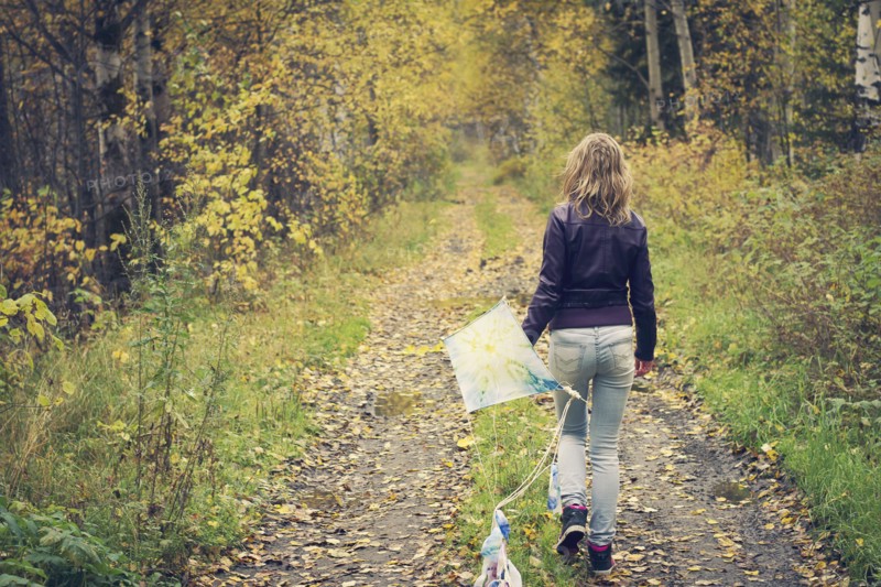 Woman carrying kite on dirt path