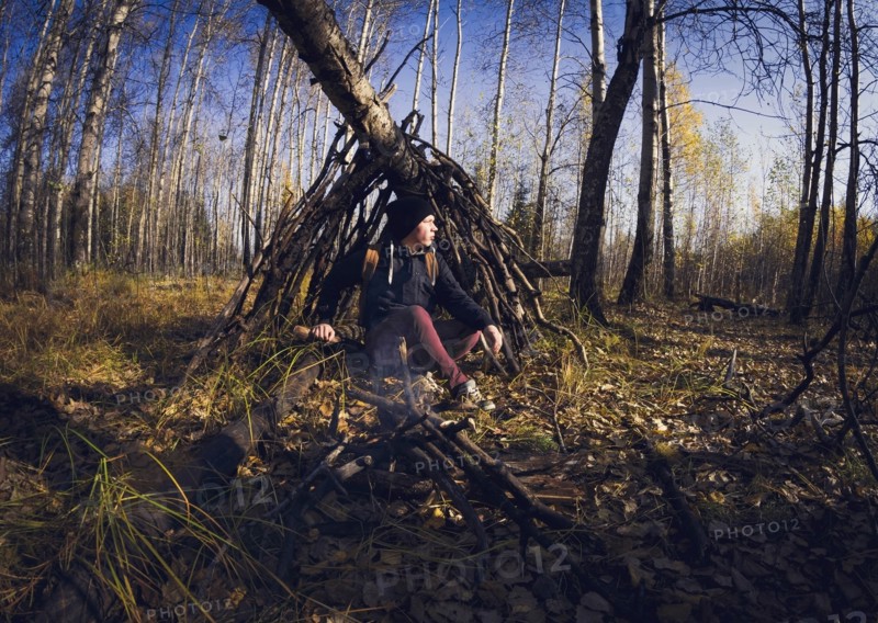 Man sitting in wooden shelter in forest