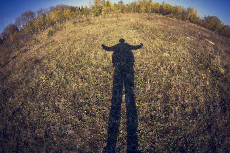 Fish-eye lens view of shadow of man in field