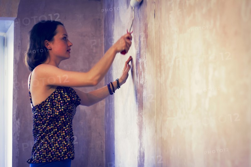 Woman painting wall with paint roller