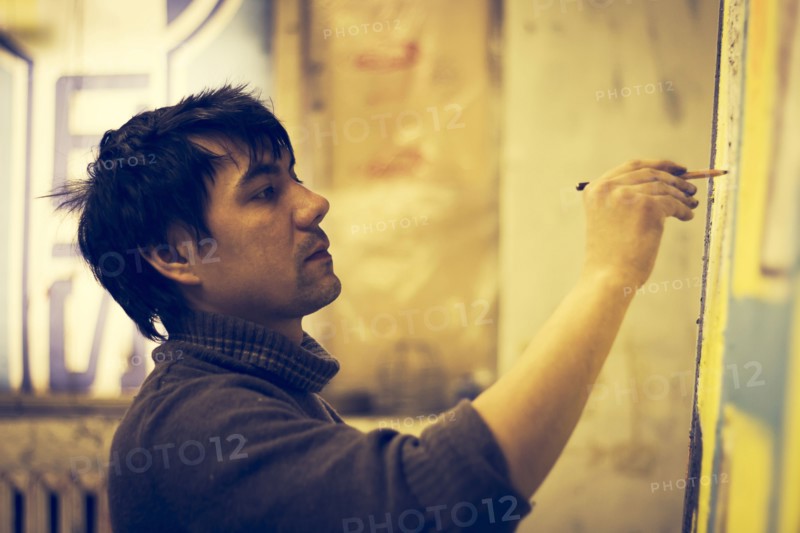 Asian artist drawing on canvas in studio