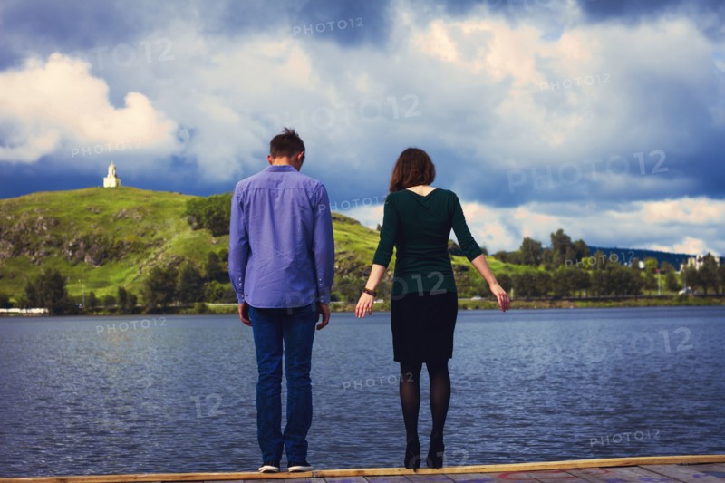 Caucasian couple standing on dock at lake