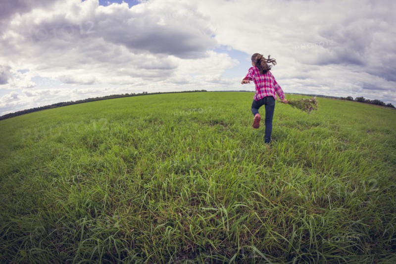 Caucasian girl running in grassy field