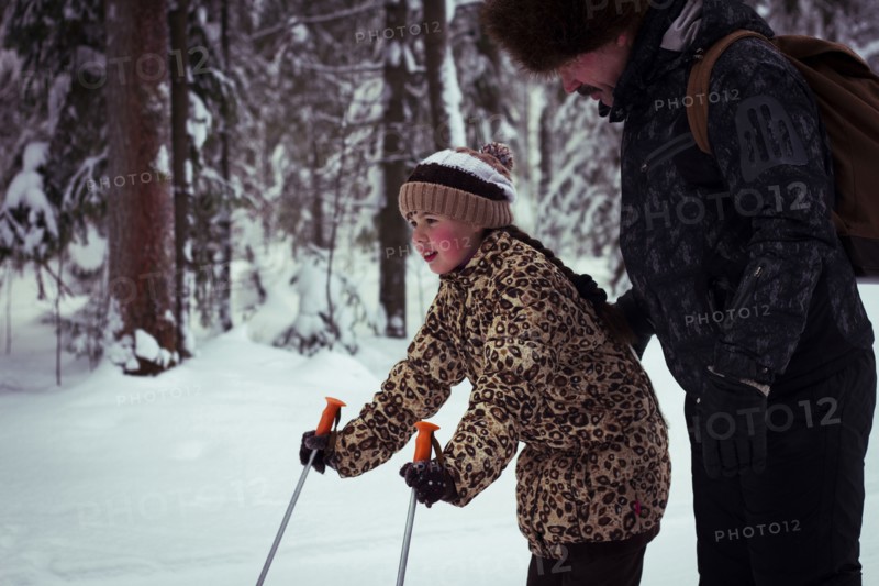 Caucasian father teaching daughter to cross-country ski in forest