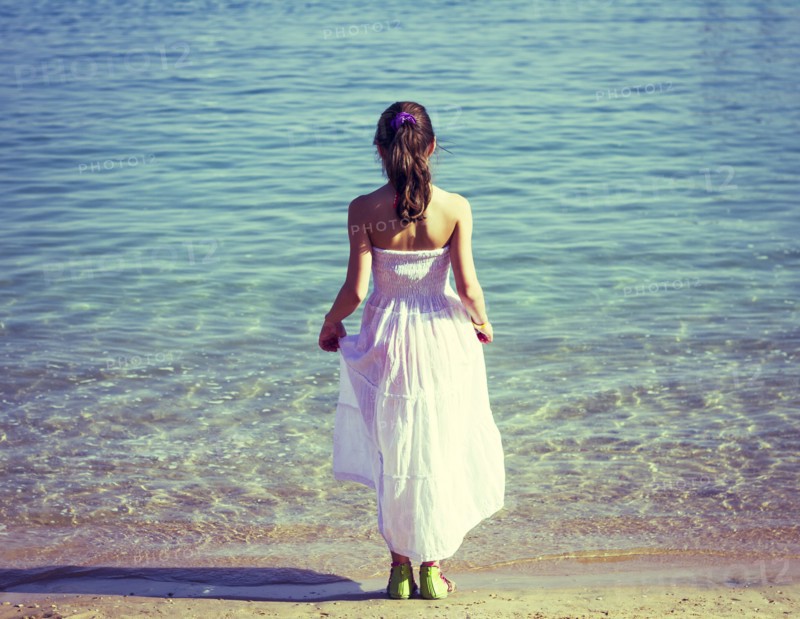 Caucasian girl wearing white dress on beach