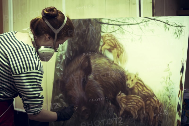 Artist in gas mask airbrushing painting in studio