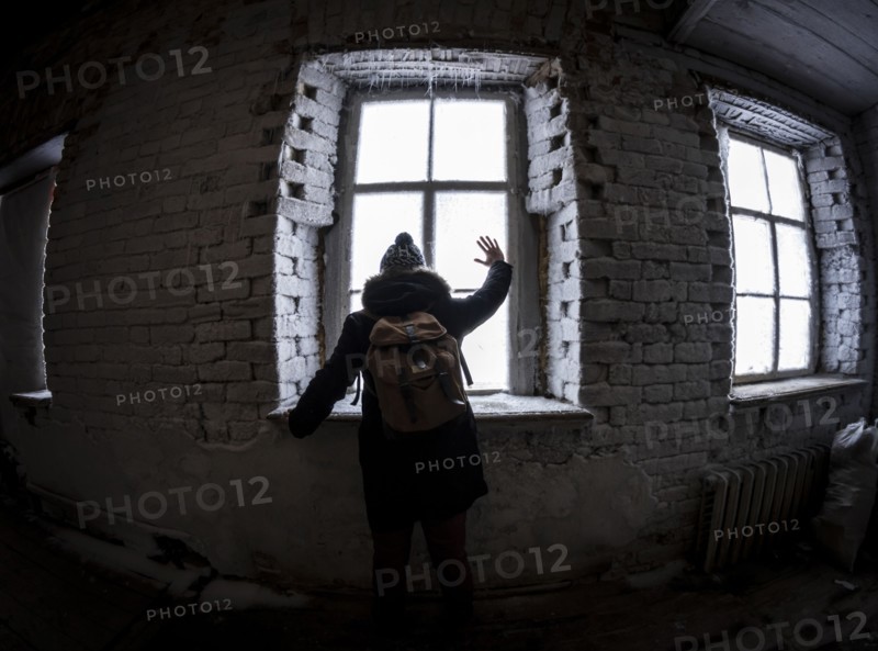 Caucasian man waving through illuminated window at night
