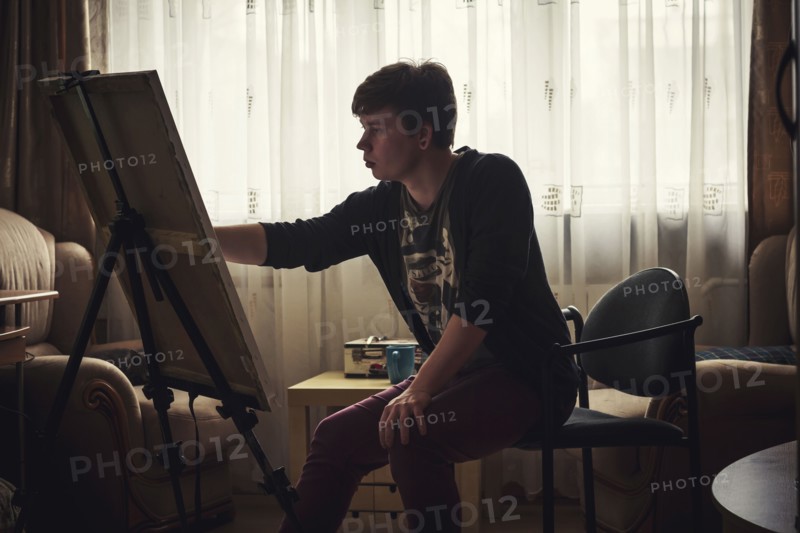 Caucasian artist painting in bedroom